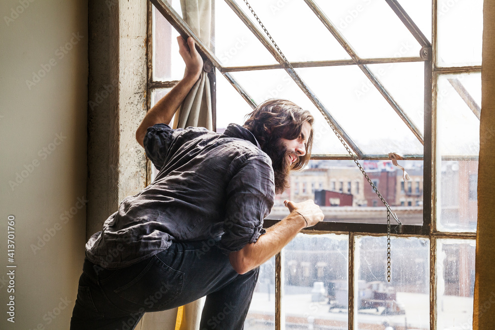 Man looking through window while standing at home