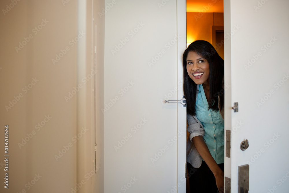 Businesswoman peeking through door at hotel room Businesswoman peeking through door at hotel room