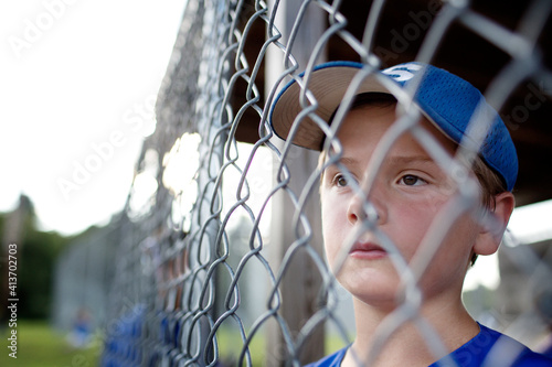 Thoughtful boy looking away while standing in dugout photo