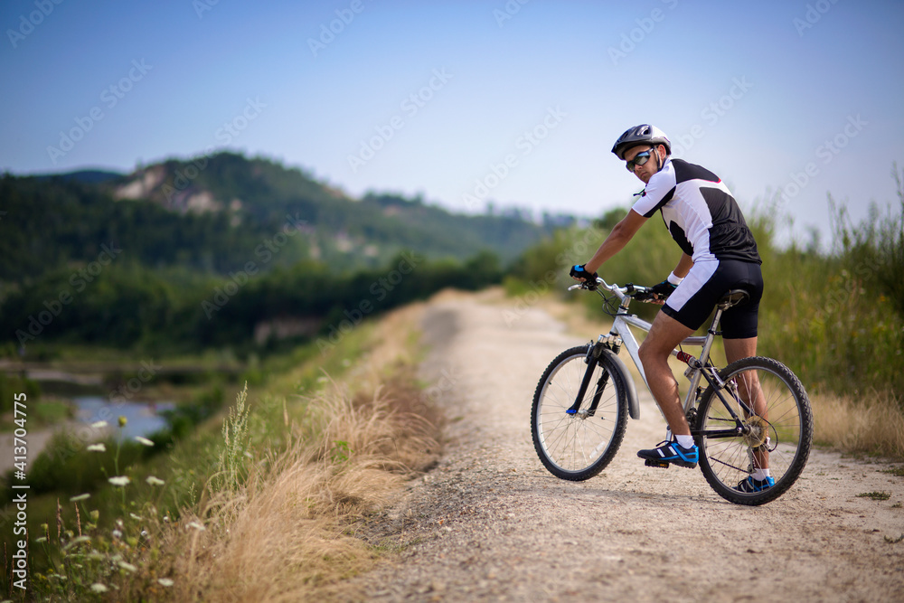 Portrait of cyclist with bicycle on dirt road Portrait of cyclist with bicycle on dirt road