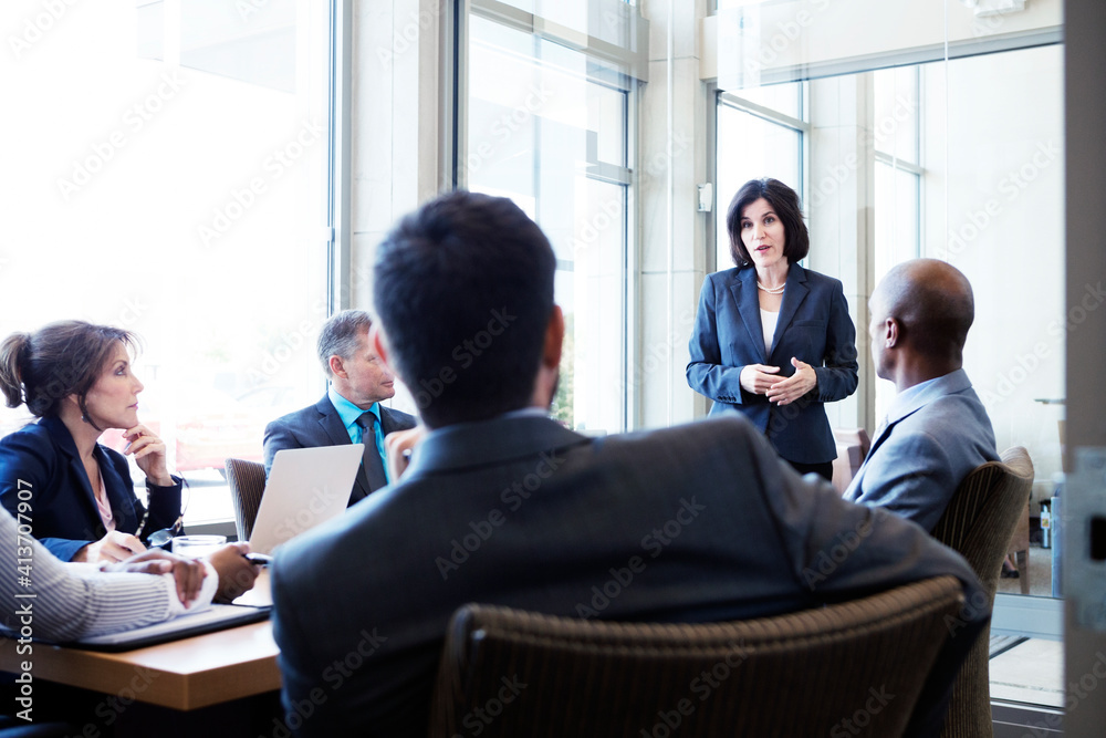 Businesswoman talking with colleagues during meeting in office Businesswoman talking with colleagues during meeting in office