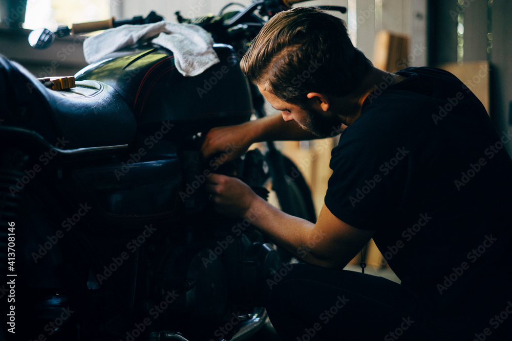 Man repairing motorcycle in garage Man repairing motorcycle in garage