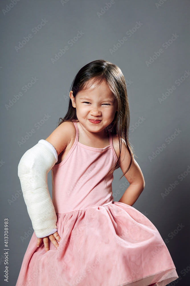 Portrait of cute girl standing with hands on hip against gray background Portrait of cute girl standing with hands on hip against gray background