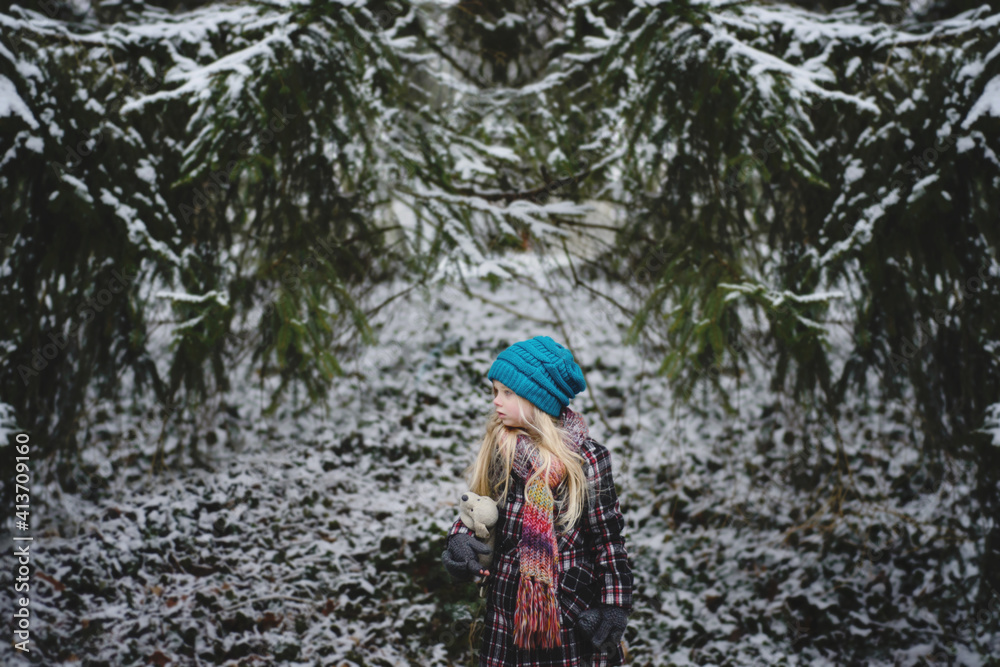 © Cavan Images - Girl with stuffed toy standing at backyard during winter