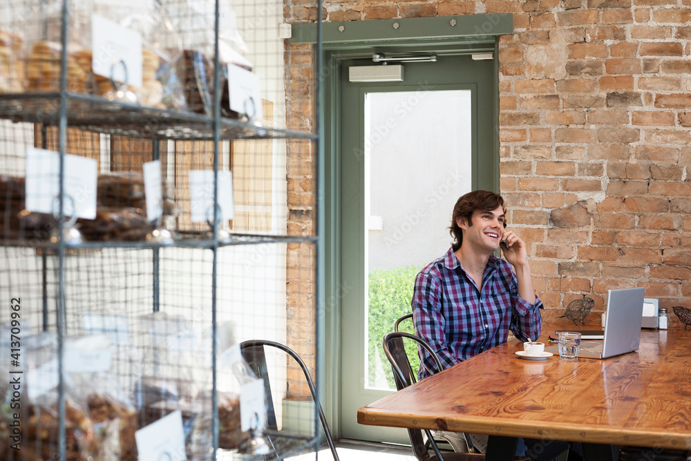 Man talking on mobile phone while sitting in coffee shop Man talking on mobile phone while sitting in coffee shop