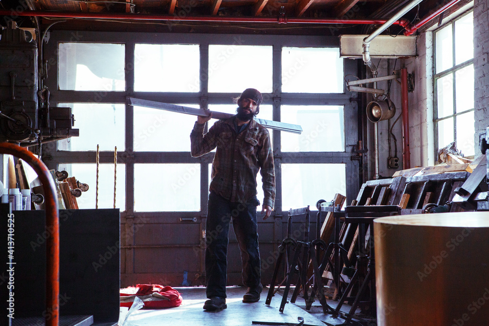 Portrait of worker carrying metal planks in workshop Portrait of worker carrying metal planks in workshop
