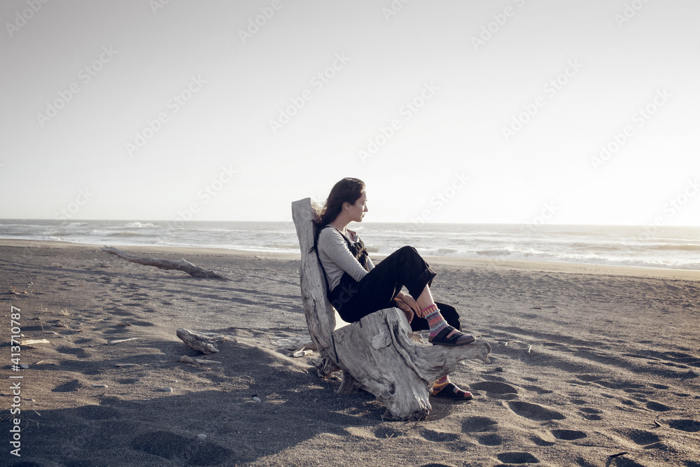 Thoughtful woman relaxing on wood at beach Thoughtful woman relaxing on wood at beach