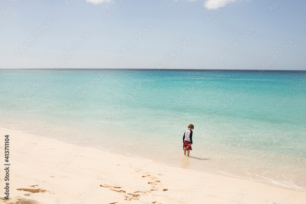 Rear view of boy standing in sea against sky Rear view of boy standing in sea against sky