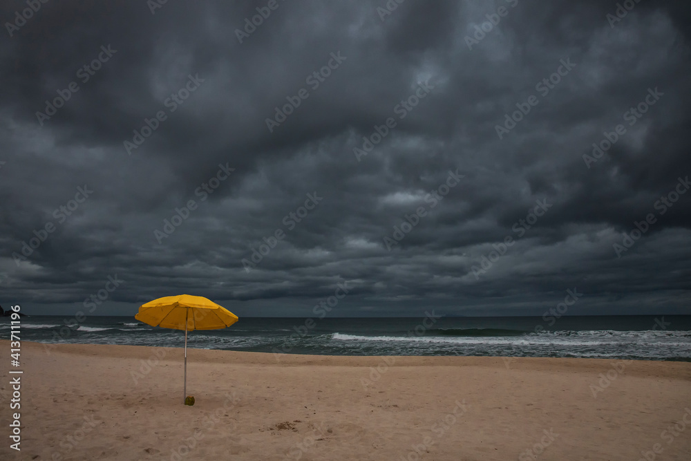 Beach umbrella on sand by sea against cloudscape Beach umbrella on sand by sea against cloudscape