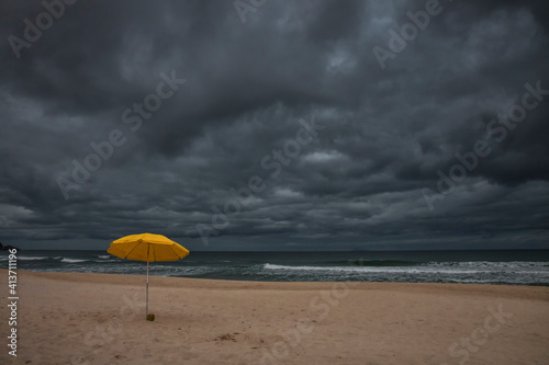 Beach umbrella on sand by sea against cloudscape photo