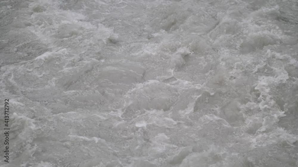 Fast streaming gray melted water in a small river and sloshing on the rocks and stones in Lauterbrunnen Switserland. Close-up shot Fast streaming gray melted water in a small river and sloshing on the rocks and stones in Lauterbrunnen Switserland. Close-up shot