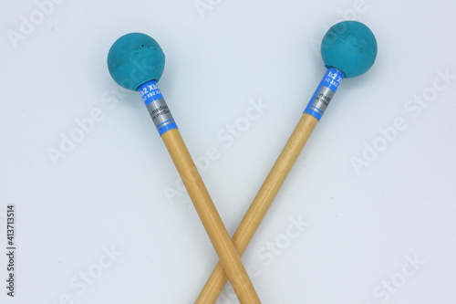 Closeup detail of crossed xylophone mallets on a white background.