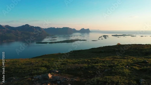 Aerial drone view passing a hiker and a tent high up in the mountains, sunset photo