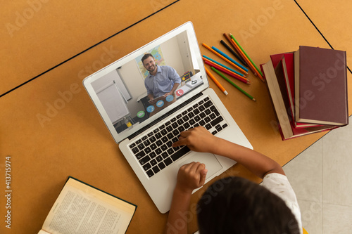 Overhead view of male student having a videocall with male teacher on laptop at home