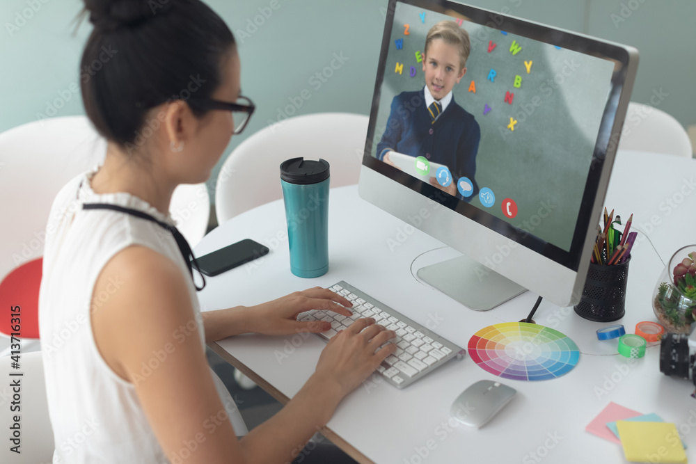 Female teacher having a video call with male student on computer at school Female teacher having a video call with male student on computer at school