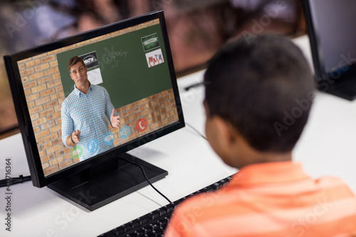 Male student having a video call with male teacher on computer at school