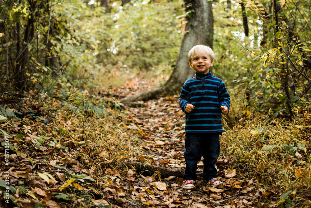 Cute boy looking up while standing on field in forest Cute boy looking up while standing on field in forest