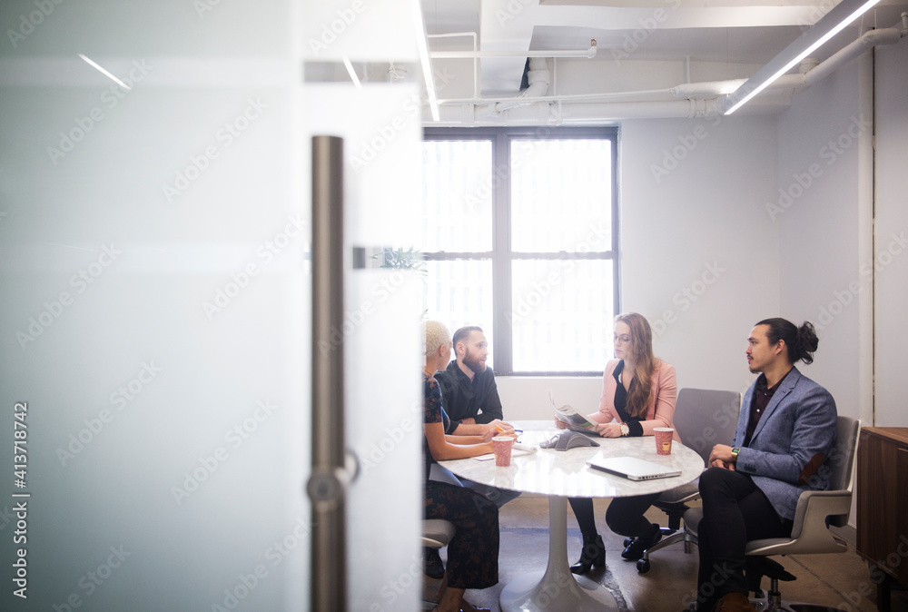 Business people discussing while sitting in office Business people discussing while sitting in office