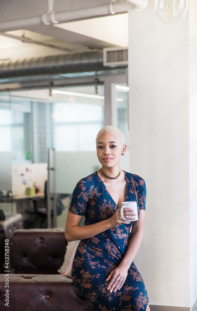 Portrait of businesswoman with coffee cup sitting on armchair in office Portrait of businesswoman with coffee cup sitting on armchair in office