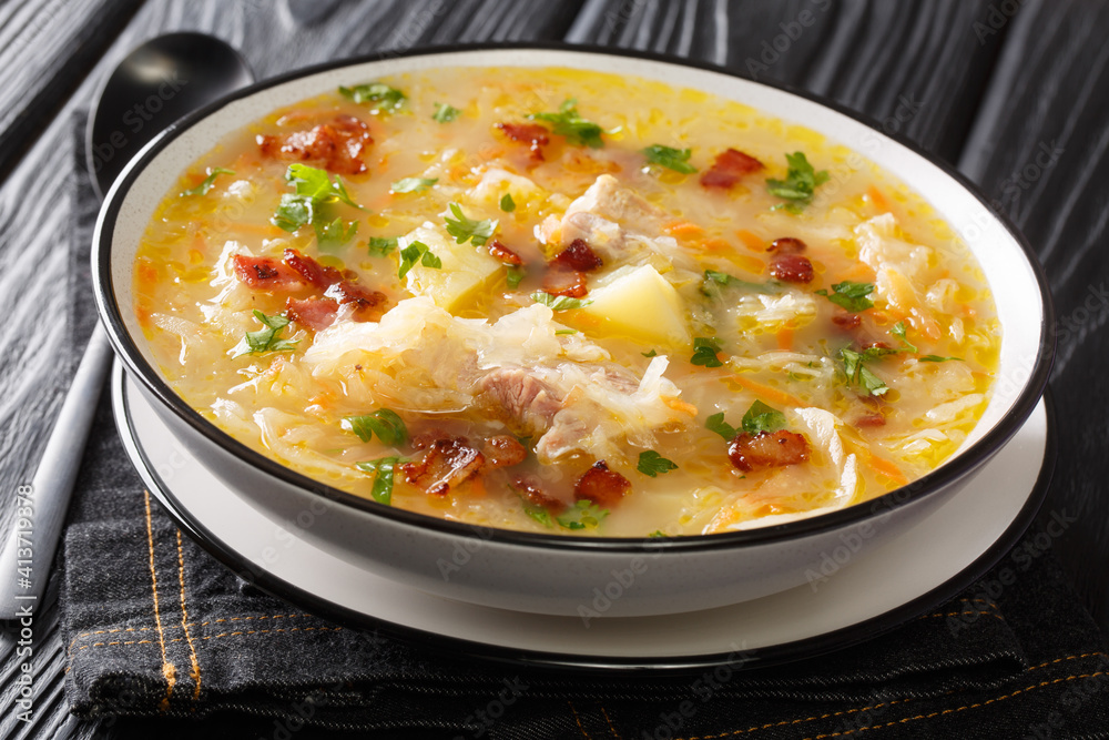 Kapusniak Cabbage soup from sauerkraut with vegetables and ribs and bacon close-up in a plate on the table. horizontal Kapusniak Cabbage soup from sauerkraut with vegetables and ribs and bacon close-up in a plate on the table. horizontal