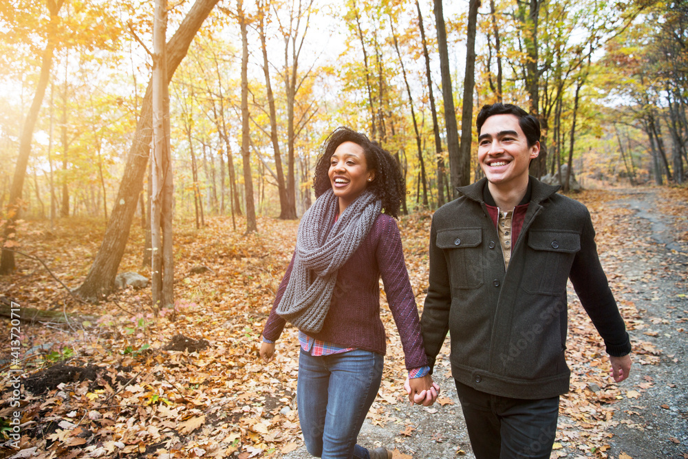 Happy couple holding hands while walking in forest Happy couple holding hands while walking in forest