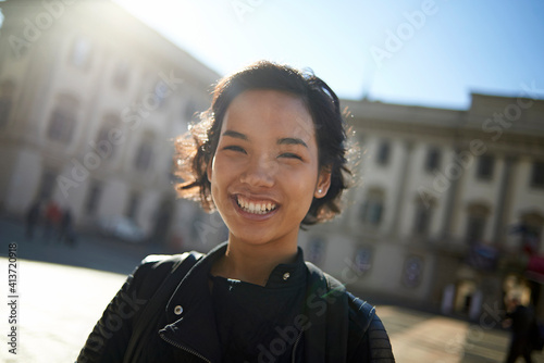 Portrait of smiling woman standing against building in city photo