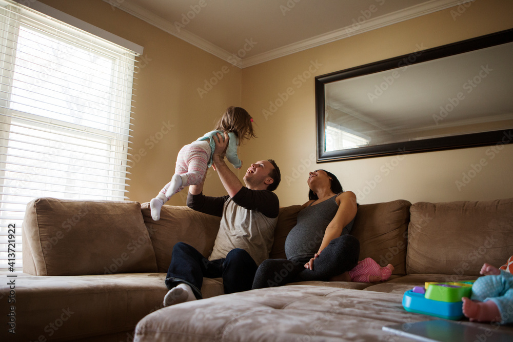 Parents playing with daughter while sitting on sofa at home Parents playing with daughter while sitting on sofa at home
