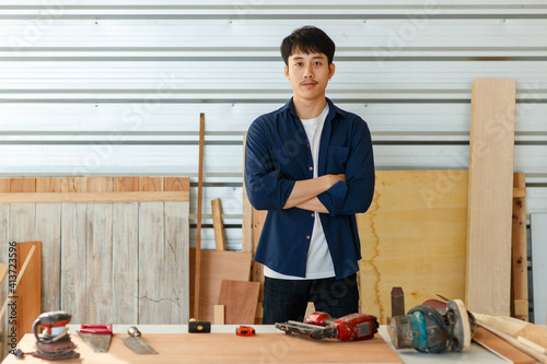 Young Asian man carpenter standing on diy room ready to work photo