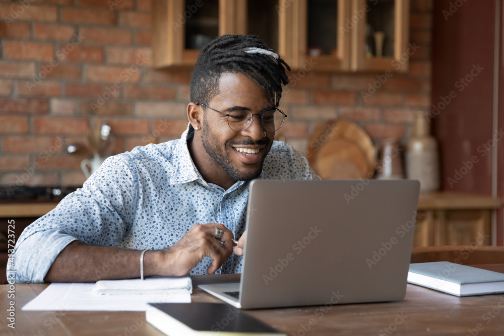 Close up smiling African American man wearing glasses using laptop, happy student watching webinar, internet course, studying at home, confident businessman working online, searching information Close up smiling African American man wearing glasses using laptop, happy student watching webinar, internet course, studying at home, confident businessman working online, searching information