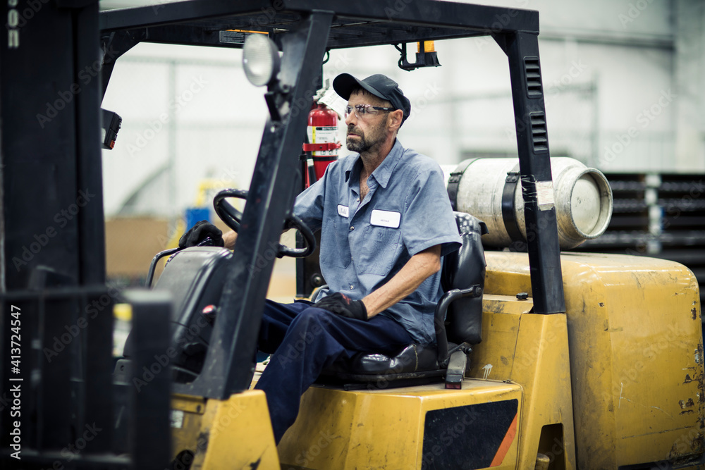 Serious manual worker sitting in forklift at metal industry Serious manual worker sitting in forklift at metal industry