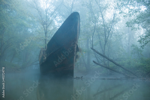 Abandoned boat on river in forest during foggy weather photo