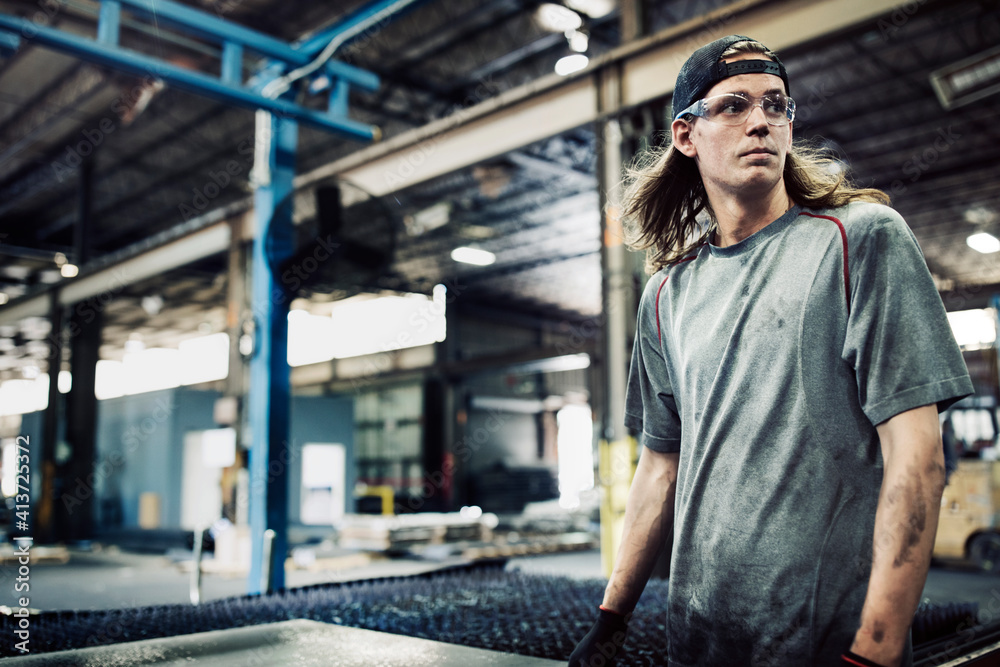 Manual worker looking away while standing in steel factory Manual worker looking away while standing in steel factory