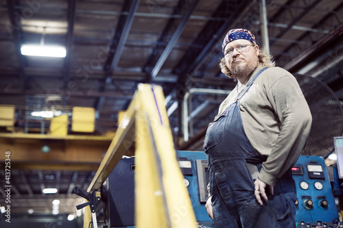 Low angle view of blue collar worker wearing bib overalls and headscarf while working in steel industry photo
