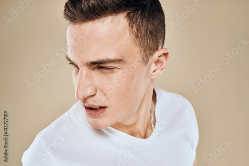 Man with displeased facial expression emotions white t-shirt gestures with hands beige background