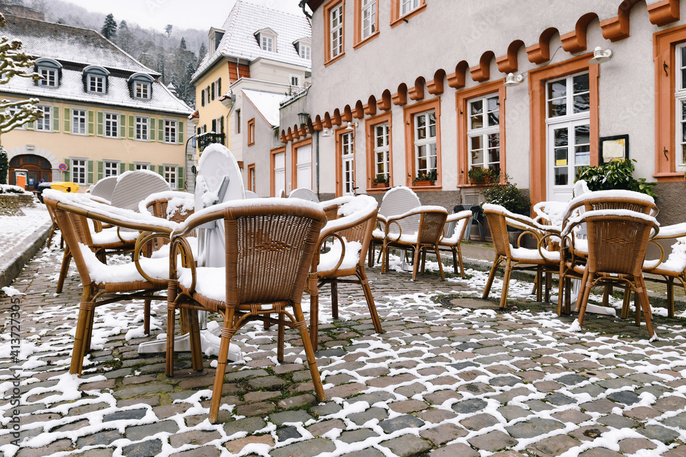 Heidelberg - Germany. Empty tables with chairs covered in snow in front of outdoor restaurant in historic city center of Heidelberg during winter