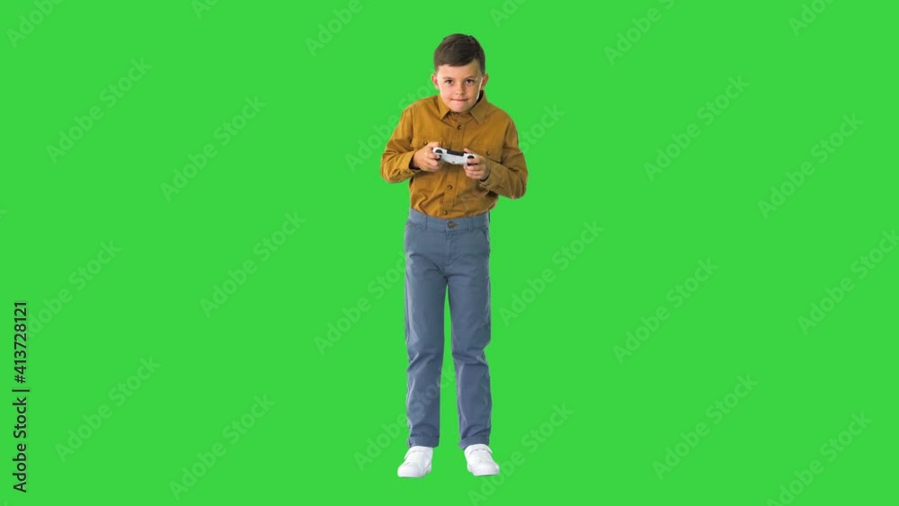 Emotional little boy playing video games with joystick in his hands on a Green Screen, Chroma Key. Emotional little boy playing video games with joystick in his hands on a Green Screen, Chroma Key.