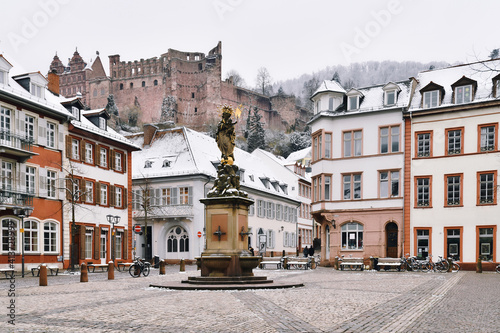 Heidelberg, Germany - Old square called 'Kornmarkt' in old city center with fountain and view on historical Heidelberg castle with snow during winter