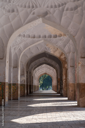 Beautiful perspective view of row of aligned arches around mughal emperor Jahangir's tomb in Char Bagh garden, Lahore, Punjab, Pakistan with side light