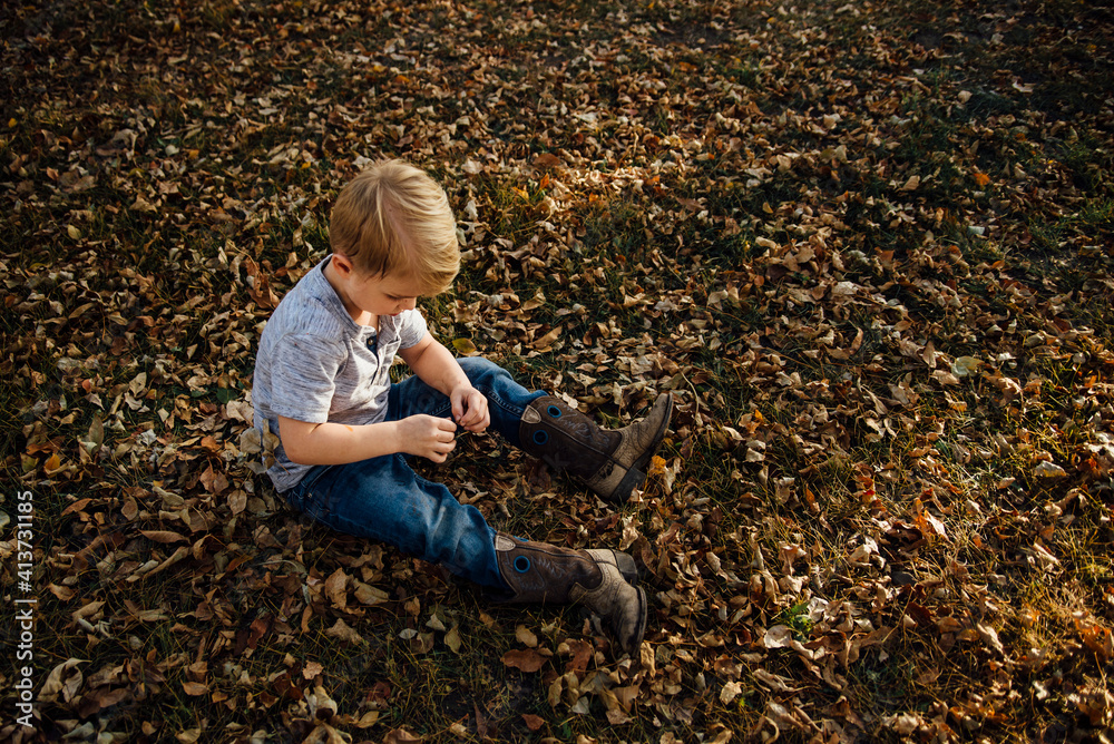High angle view of boy sitting on fallen autumn leaves at park High angle view of boy sitting on fallen autumn leaves at park