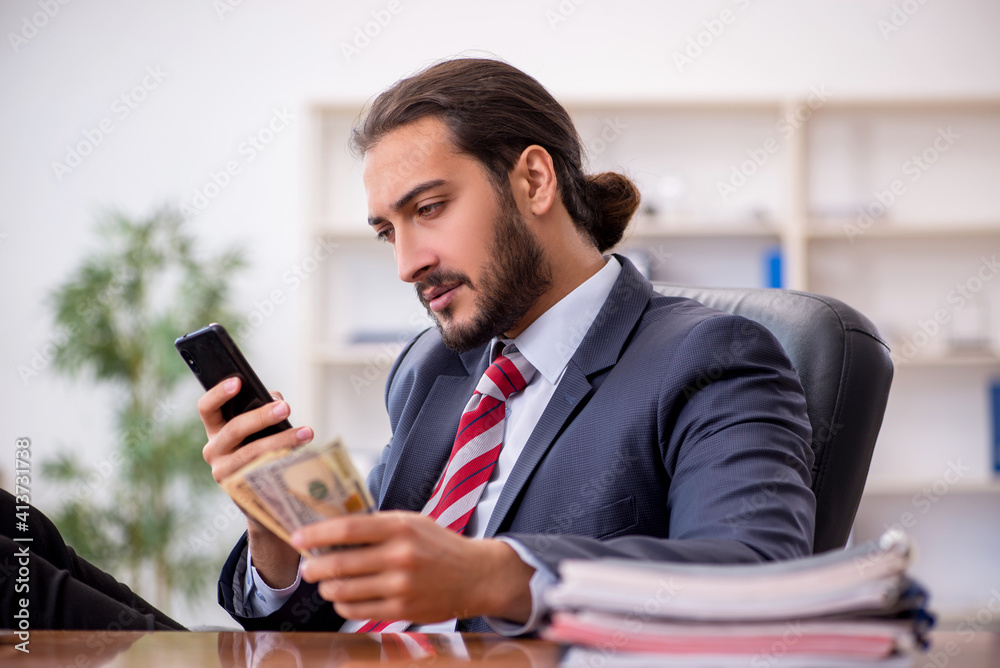 Young male employee holding banknotes in the office Young male employee holding banknotes in the office