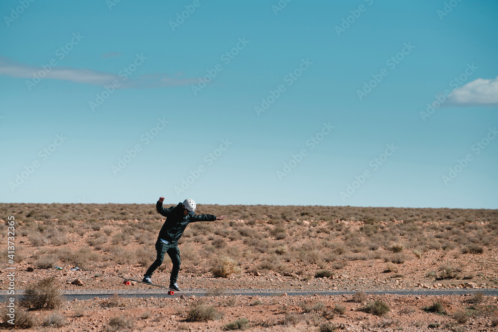 Man skateboarding on road amidst field against sky Man skateboarding on road amidst field against sky