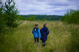 summer forest, field, nature,, two children in blue jackets stand in a field, field in June