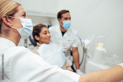 Female dentist with face mask showing x-ray to patient