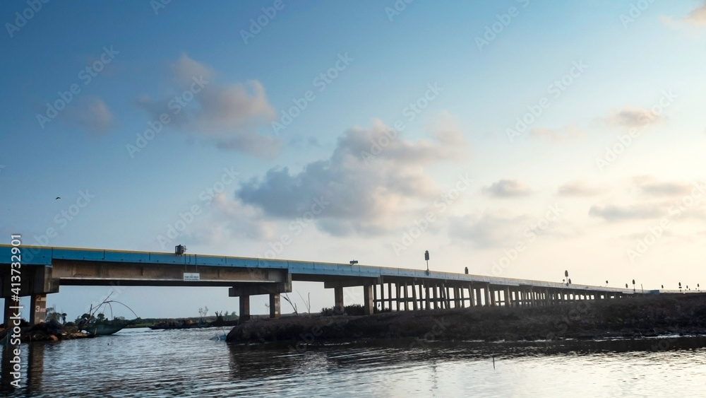 Concrete bridge cross the sea with sunset background.