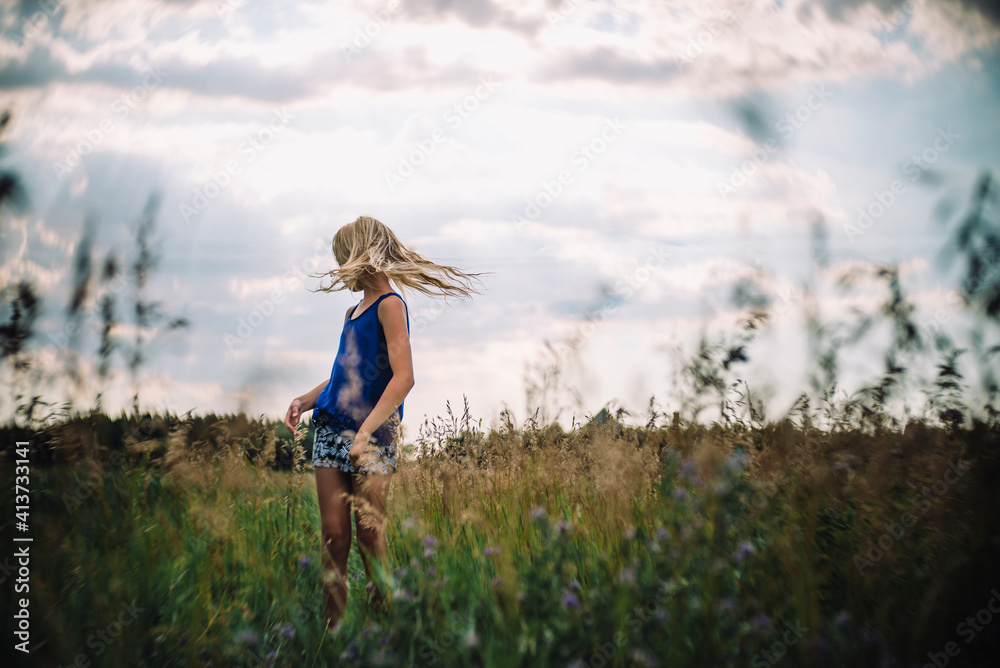Girl tossing hair while standing on field against sky Girl tossing hair while standing on field against sky