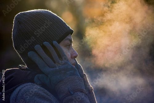 Close-up of woman exhaling breath vapor at park during winter