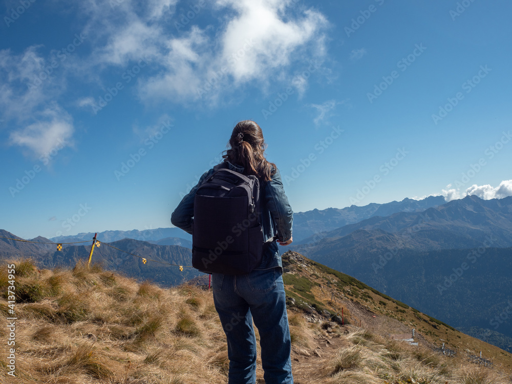 young female tourist with a backpack is walking in the mountains, traveling in national parks.