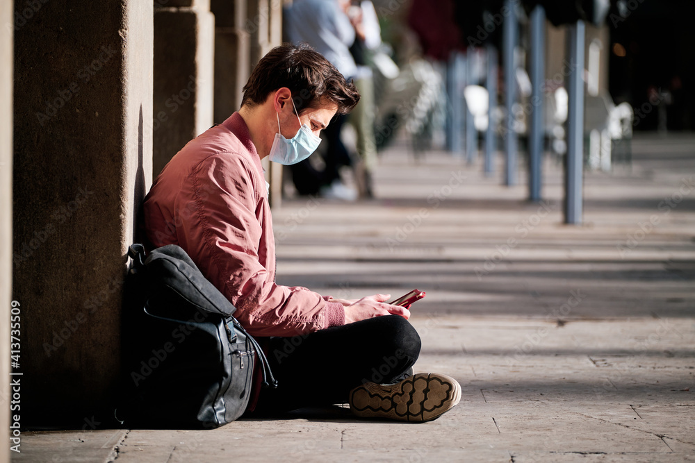 Man wearing a face mask and using a digital tablet outdoors.