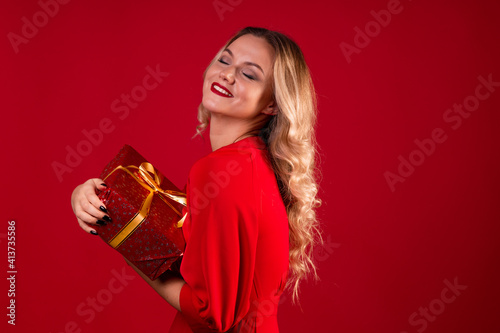 Get a gift, a happy young woman in a red dress got a nice surprise for new year, Christmas or birthday.