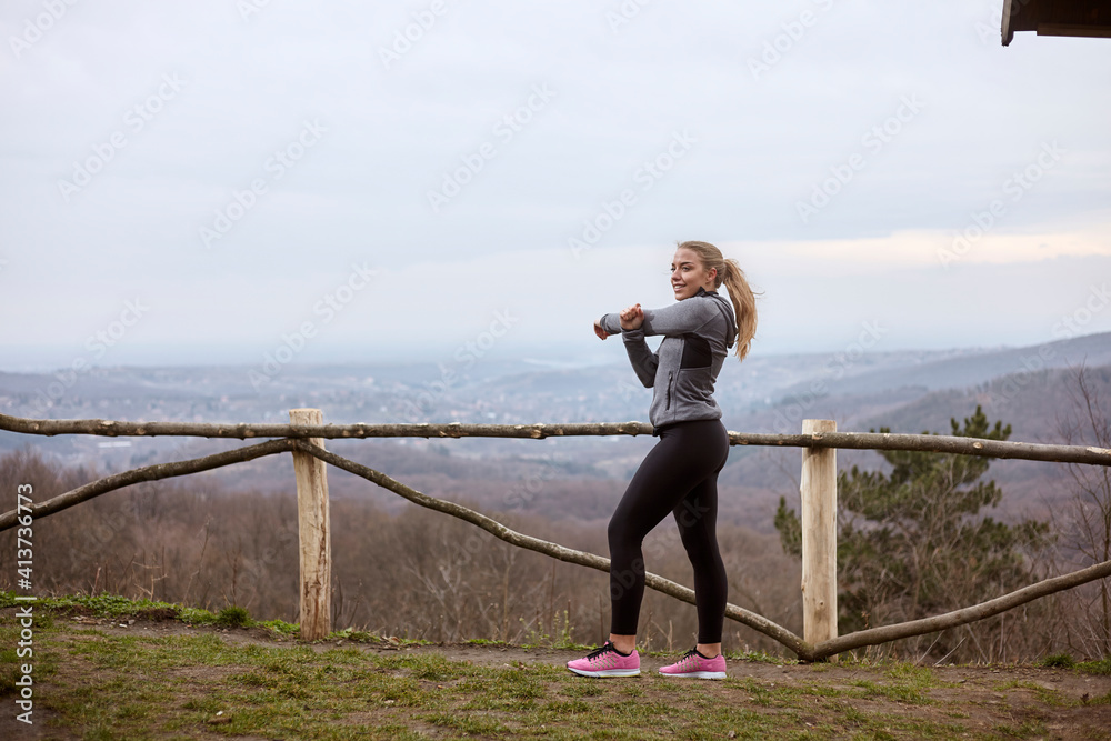 Woman exercising while standing on field against cloudy sky at Fruska Gora National Park Woman exercising while standing on field against cloudy sky at Fruska Gora National Park